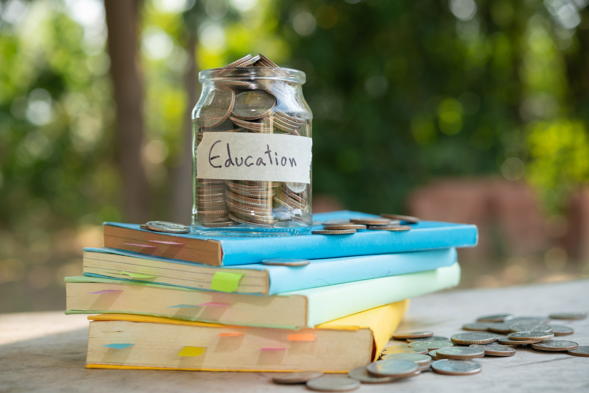 putting money coins saving in glass bottle for concept investment mutual fund finance and business, placed on the textbook. content money saving for education.